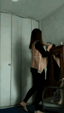 a woman is standing in front of a closet holding a purse
