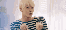 a young man wearing a striped shirt is making a funny face .