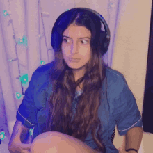 a woman wearing headphones is sitting in front of a purple curtain