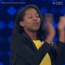a woman applauds while wearing a name tag that says " family feud canada "