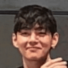 a close up of a young man making a funny face while holding his hand to his chin .