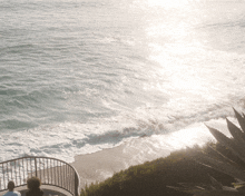 a couple sits on a balcony overlooking a body of water