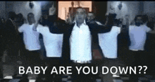 a man in a white shirt is standing in front of a group of people holding their arms in the air .