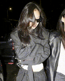 a woman wearing sunglasses is standing next to another woman in a black jacket