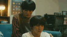 two young men are sitting on a couch and one has his arm around the other