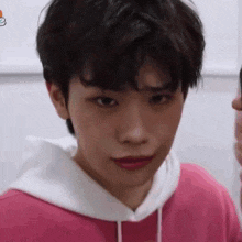a close up of a young man wearing a pink hoodie .