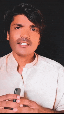 a young man in a white shirt is holding a cell phone