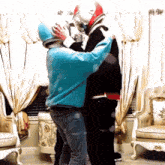 a man in a blue sweater is hugging another man in a black jacket