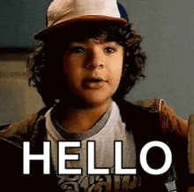 a young boy with curly hair is wearing a hat and a jacket and saying `` hello '' .