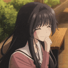 a girl with long black hair is smiling with her hand to her chin