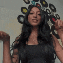 a woman with long dark hair is dancing in front of a wall with records on it .