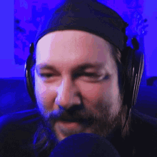 a man with a beard wearing headphones and a black hat