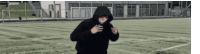 a man in a hoodie is running on a soccer field .