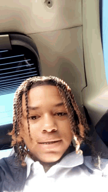a young man with braids is taking a selfie in the back of a car