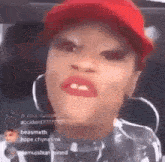 a close up of a woman wearing a red hat and hoop earrings making a funny face .