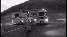a black and white photo of people standing in front of a rv with the letter a on it
