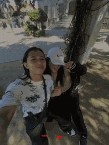 a girl wearing a white nike hat stands next to another girl