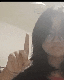 a woman wearing glasses is making a middle finger gesture .