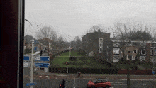 a red car is driving down a street in front of a sign that says ' amsterdam '