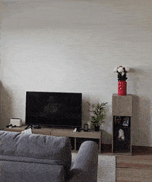 a living room with a flat screen tv and a vase of flowers on a shelf