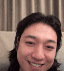 a man with long hair is smiling and looking at the camera .
