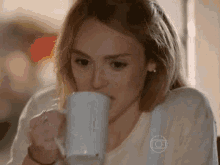 a woman is drinking a cup of coffee from a mug .