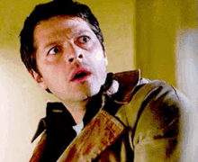 a man with a surprised look on his face is wearing a brown jacket and tie .
