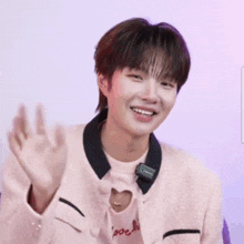 a young man wearing a pink jacket and a pink shirt with a heart cut out on the chest is smiling .