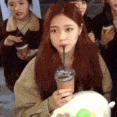 a woman is drinking a drink through a straw while sitting on a stuffed animal .