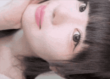 a close up of a woman 's face with a pink lip and black hair .