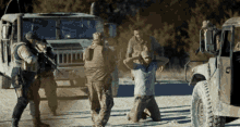 a man is kneeling in front of a military vehicle