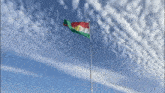 a kurdish flag flies in the wind against a cloudy sky