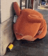 a stuffed animal is leaning against a wall with a yellow sticker on it that says caution