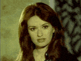a woman with long dark hair is looking at the camera