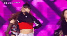 a girl in a red crop top is dancing on a stage in front of a purple background with the show written on it