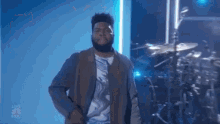 a man with a beard is standing on stage in front of a drum set .