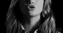 a black and white photo of a woman blowing a kiss .