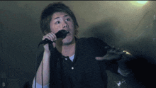a man singing into a microphone with the letter d in the bottom right corner