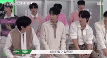 a group of young men are sitting in front of a green sign that says sbs