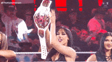 a woman is holding a wrestling championship belt in her hand .