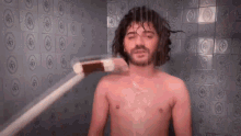 a shirtless man is taking a shower with a brush and soap .