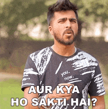 a man with a beard is wearing a black and white shirt that says " you now "