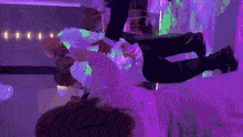 a bride and groom are dancing in a room with purple lighting