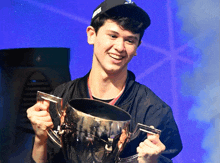 a man in a black hat is holding a trophy and smiling