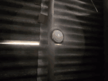 a white button is sitting on a metal wall