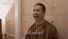 a man in a brown shirt is laughing with the word alcohol written below him