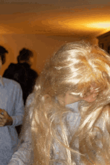 a woman wearing a blonde wig is standing in a room with other people