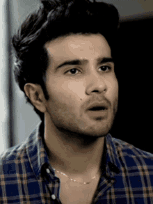 a man wearing a plaid shirt and a chain around his neck