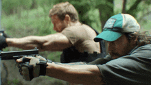 a man in a blue hat is holding a gun in his right hand