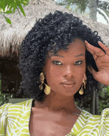 a woman with curly hair is wearing a green and white shirt